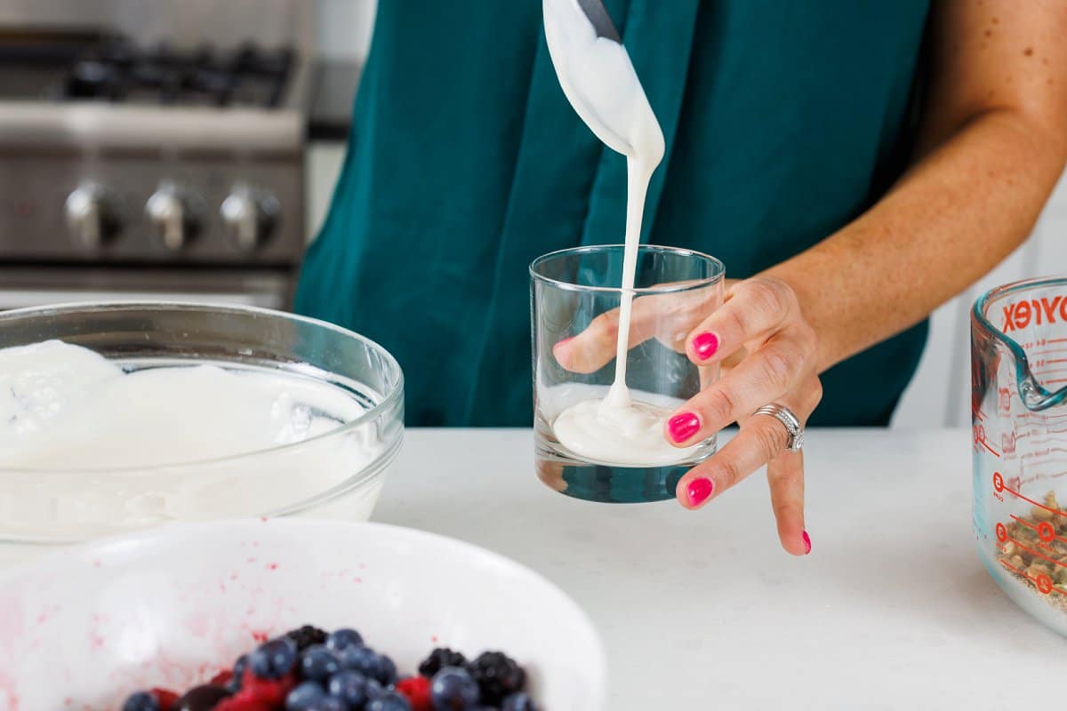 Adding yogurt to the bottom of a glass cup.
