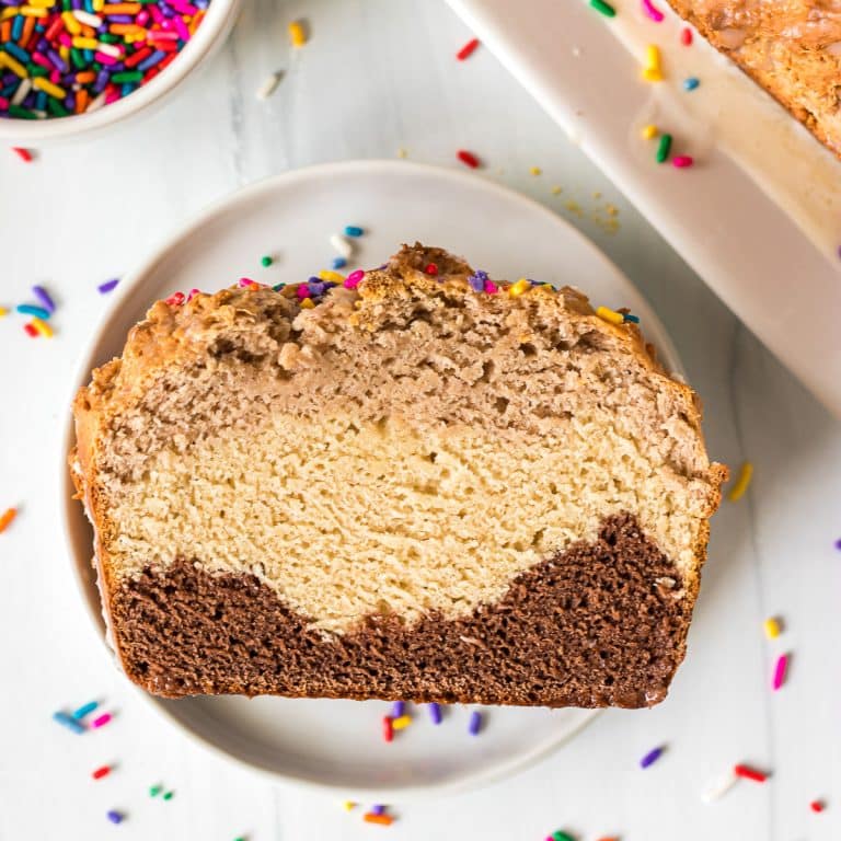 closeup of a slice of layered neapolitan ice cream bread on a white plate.