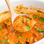 a ladle scooping butter chicken out of a crockpot.