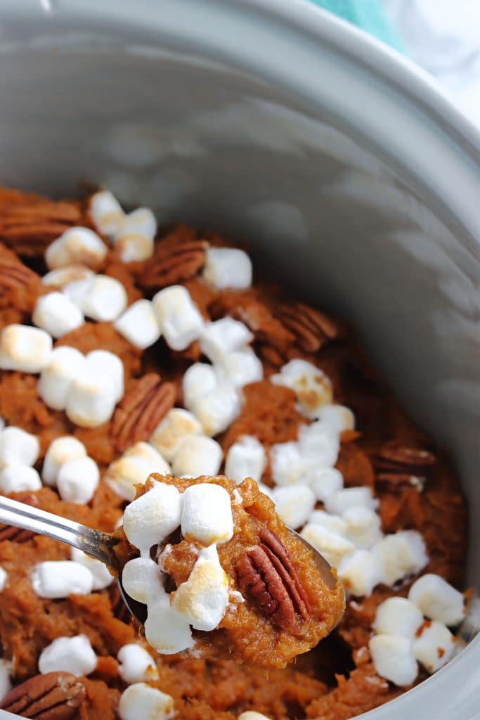 spoon lifting sweet potato casserole from a crockpot.