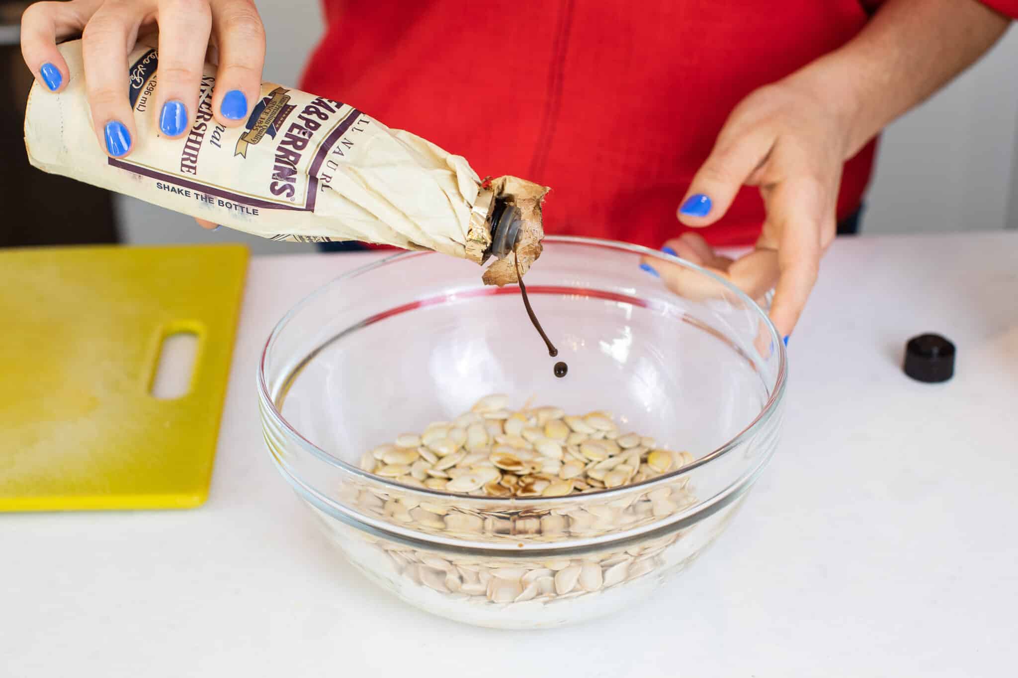 Adding Worcestershire sauce to pumpkin seeds.