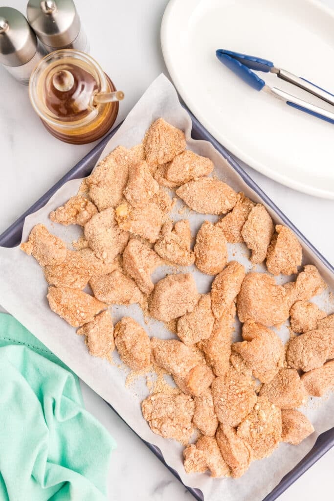 raw, breaded chicken on a baking sheet.