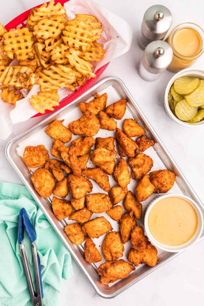 platter of chicken nuggets with sauce, waffle fries, and pickles.