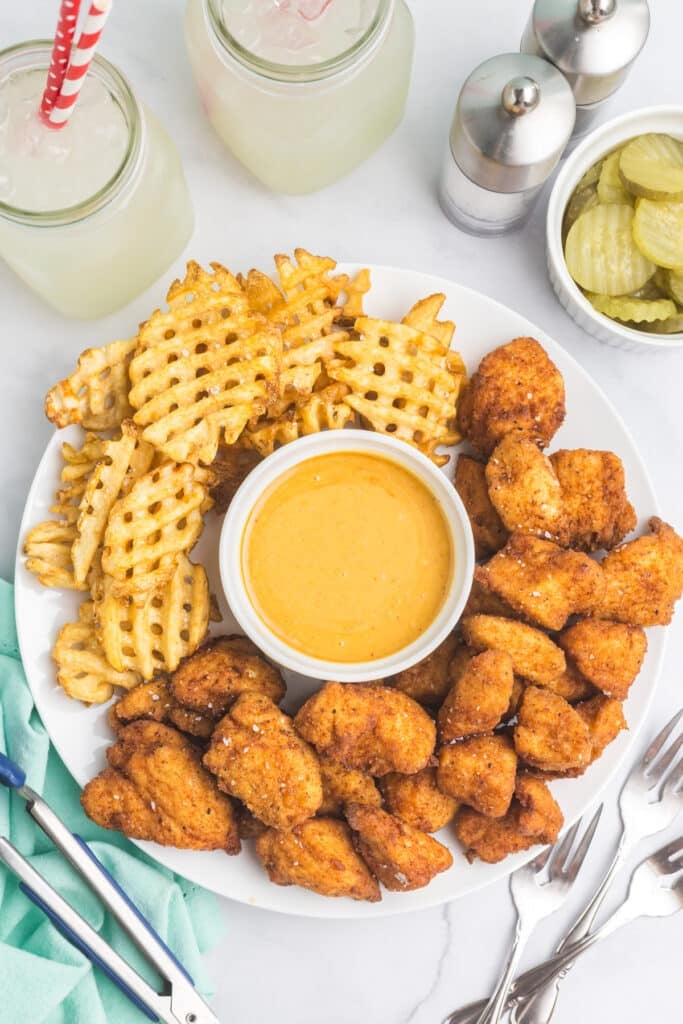 plate of copycat chick fil a chicken nuggets with a cup of sauce and waffle fries.