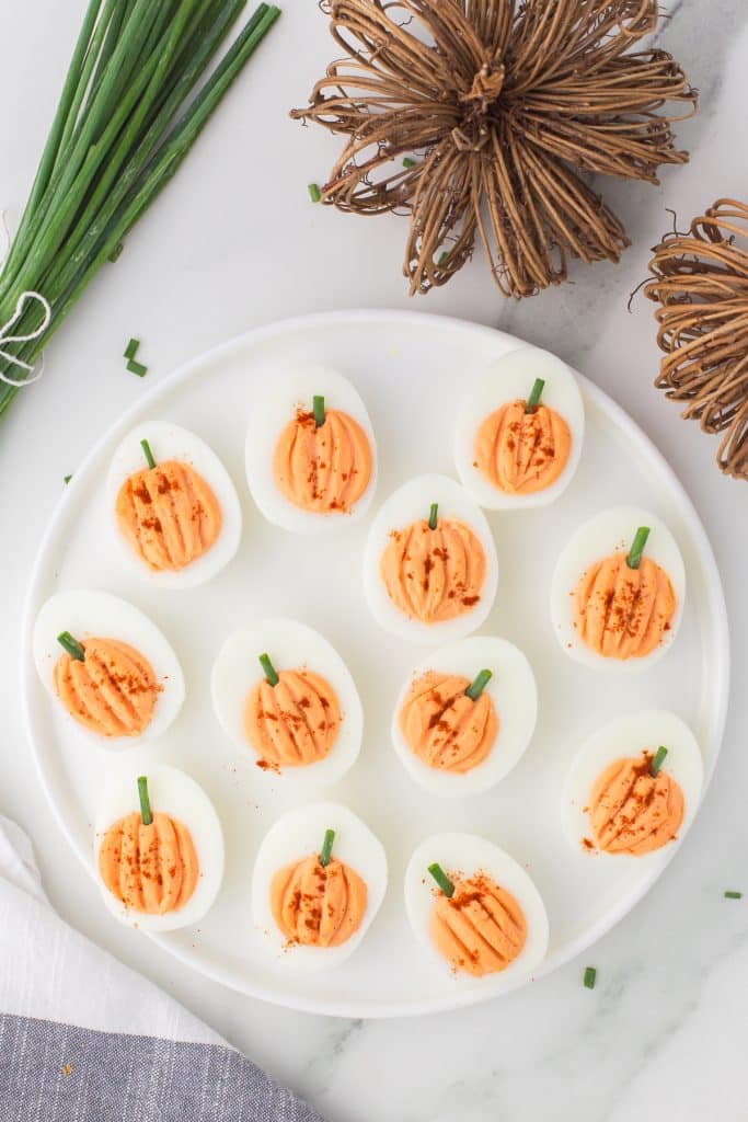 halloween deviled eggs on a white platter.
