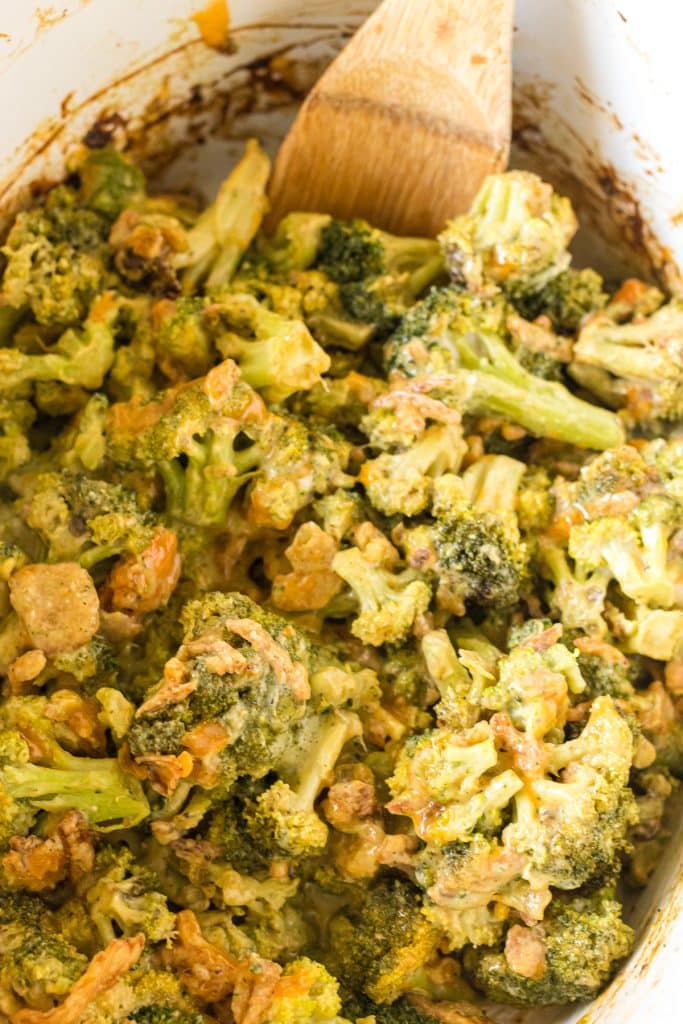 overhead shot of a wooden spoon in crockpot broccoli casserole.
