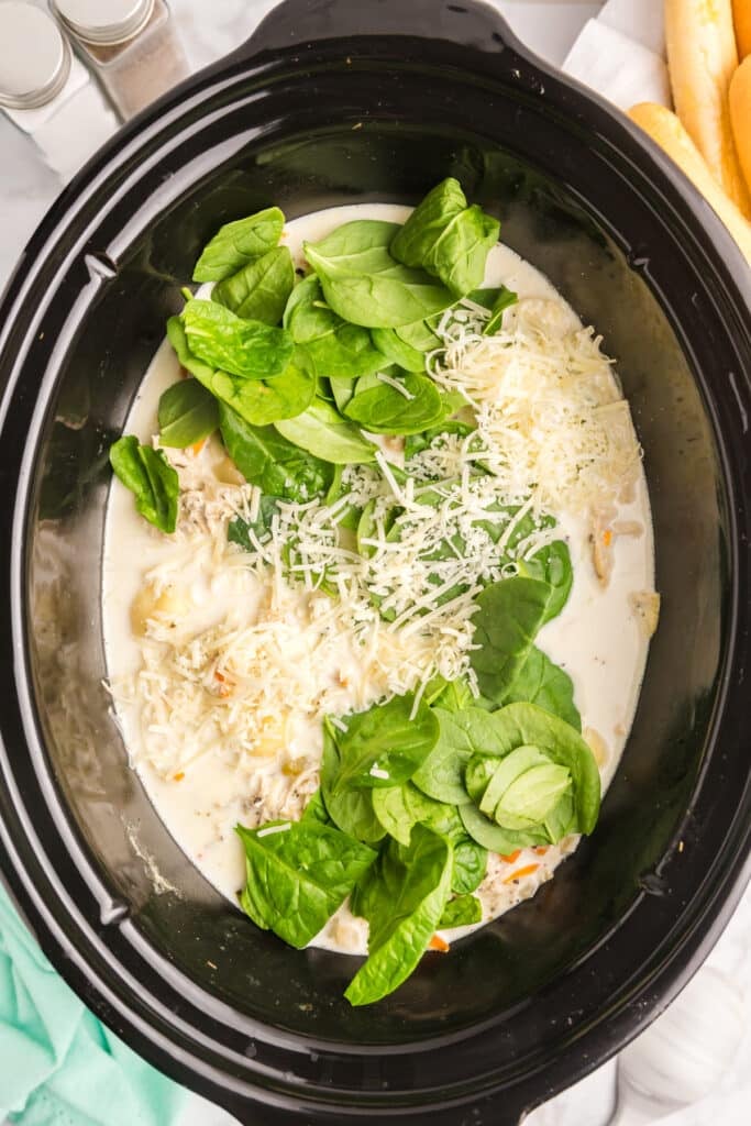 spinach, parmesan cheese, and cream in a crockpot.