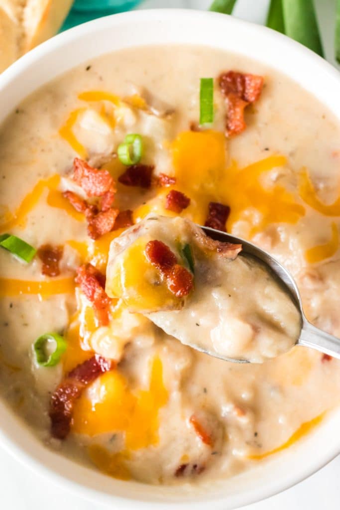 spoon lifting a bite of potato soup from a bowl.