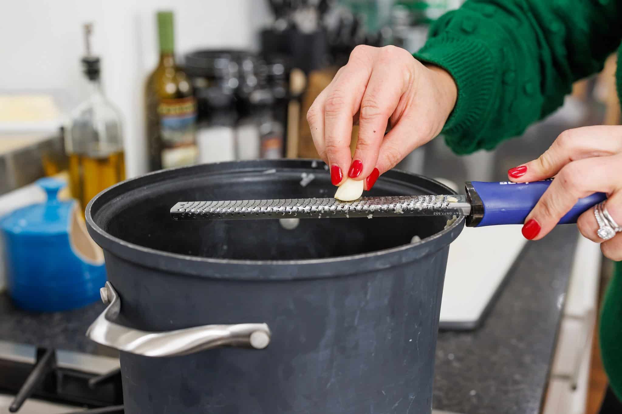 Using a microplane to grate garlic into a pot.