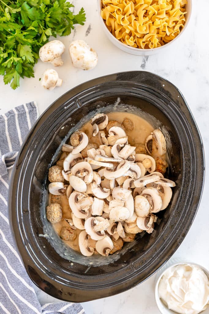overhead shot of sliced mushrooms in a crockpot.
