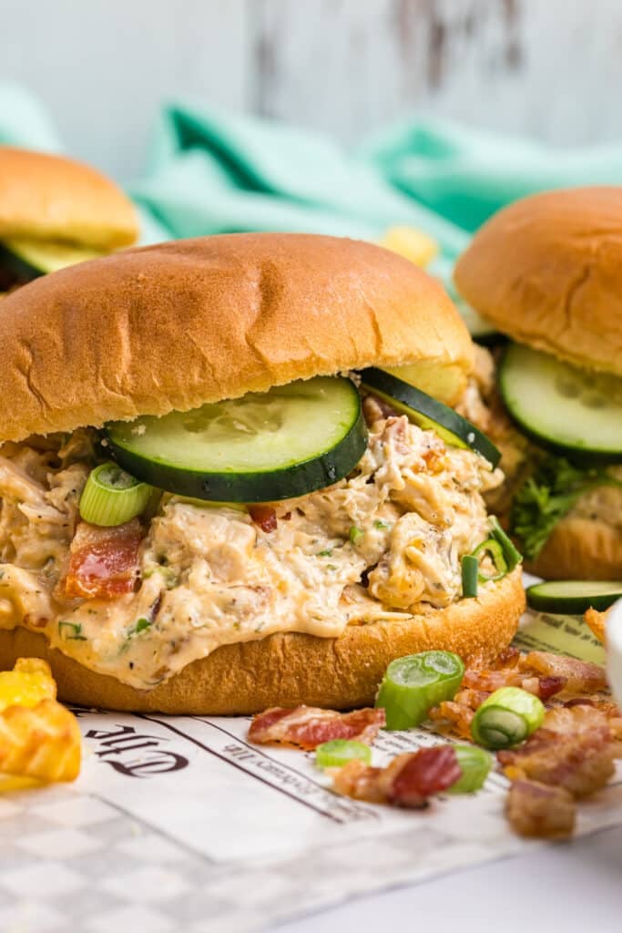 chicken bacon ranch sandwich topped with cucumbers on a bun.