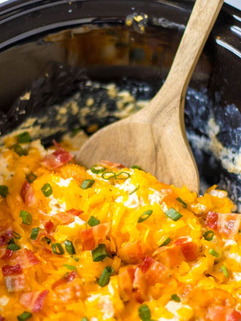 wooden spoon scooping crack chicken from a crockpot.