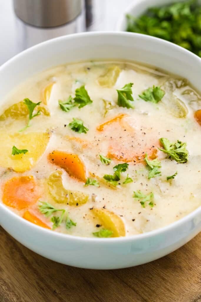closeup of a bowl of dill pickle soup topped with pepper & parsley.