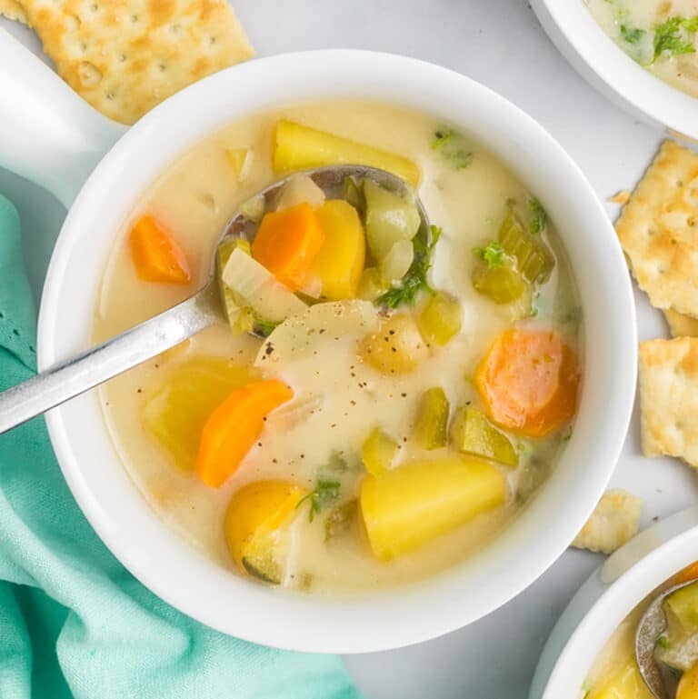 overhead shot of dill pickle soup in a white bowl.