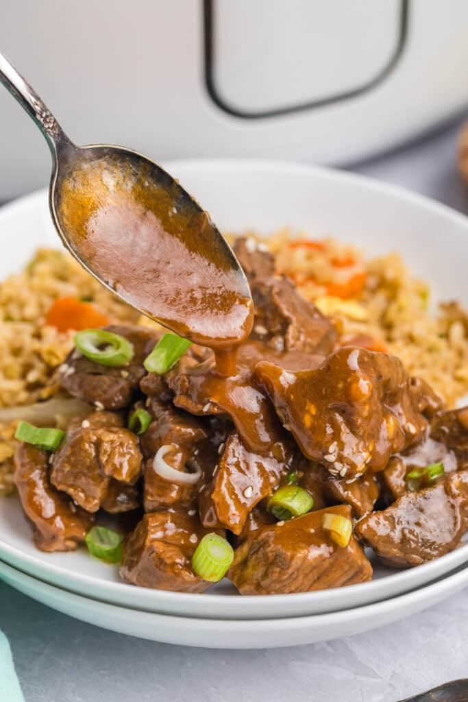 spoon pouring sauce over honey garlic steak bites.