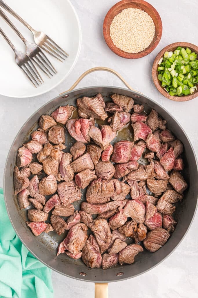 beef cubes searing in a skillet.