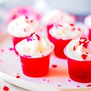 red & pink jello shots with whipped cream and valentine sprinkles.