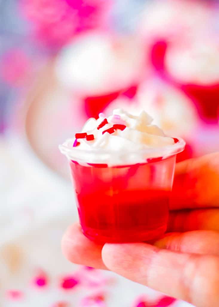 hand holding a red & pink jello shot.
