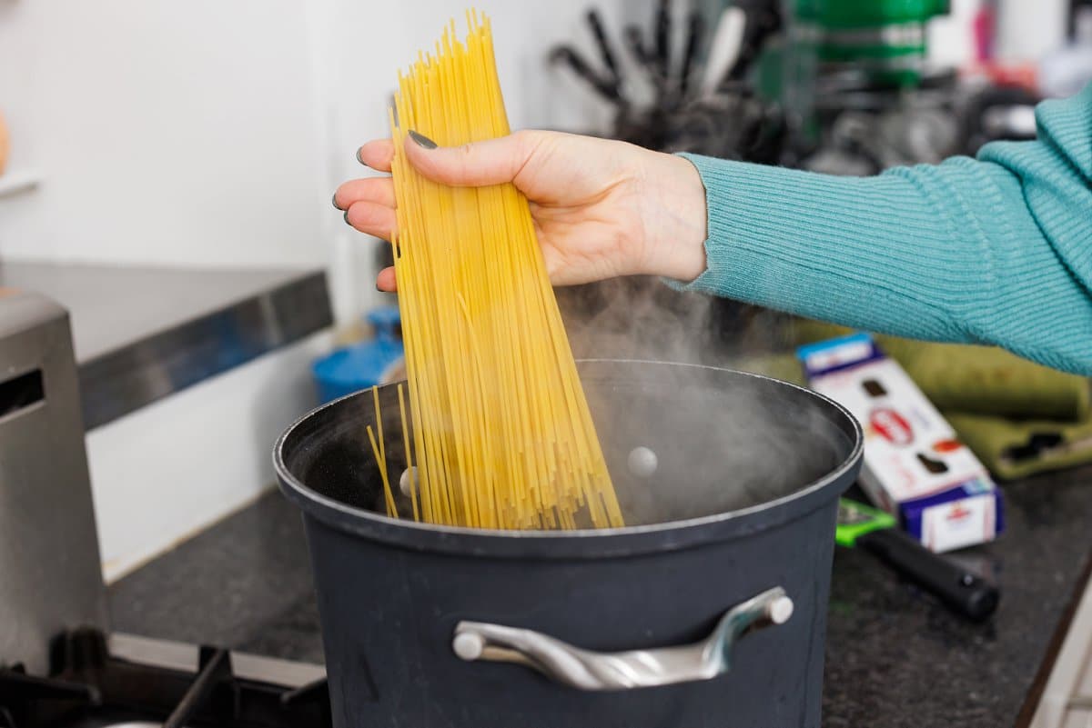 Liz adding spaghetti to pot of boiling water.