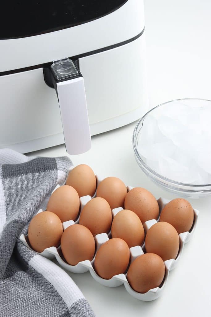 a dozen eggs next to an air fryer and ice bath.