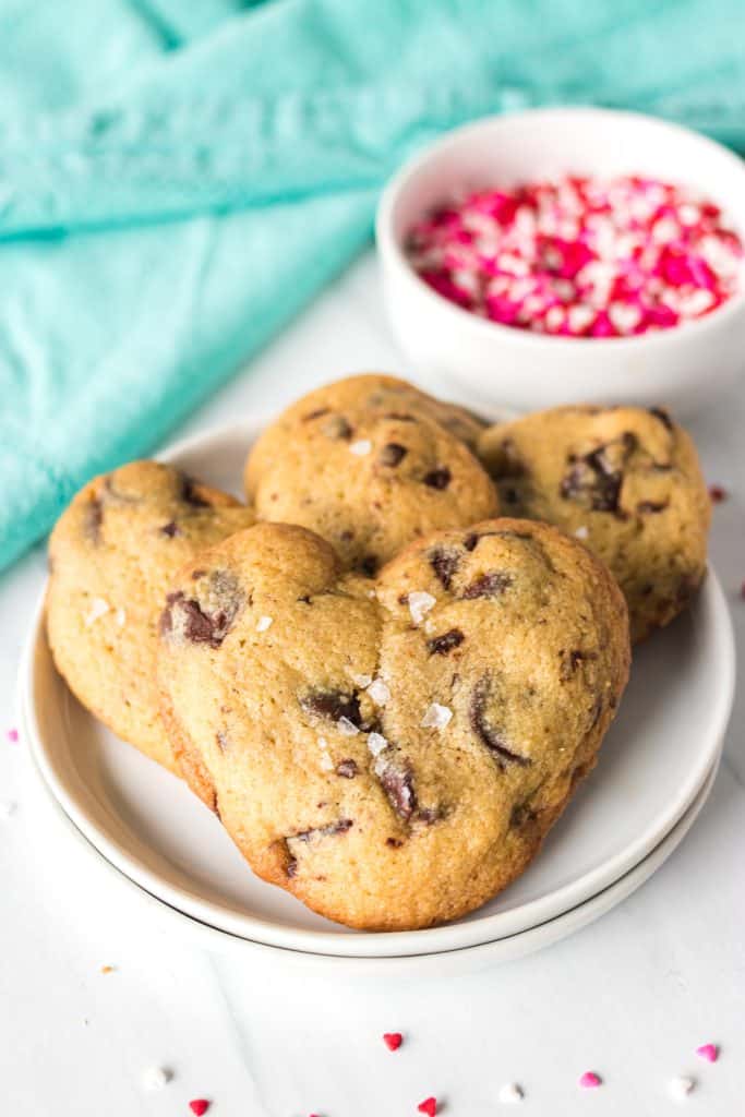 plate of heart shaped chocolate chip cookies and a bowl of pink sprinkles.
