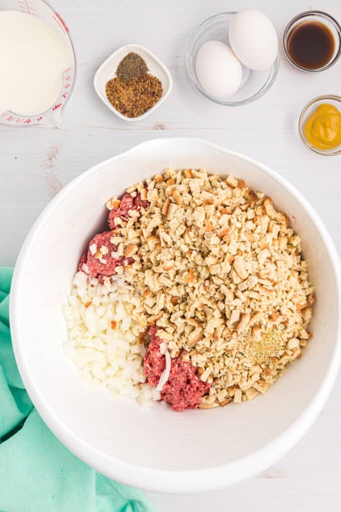 overhead shot of ground beef and breadcrumbs in a mixing bowl.
