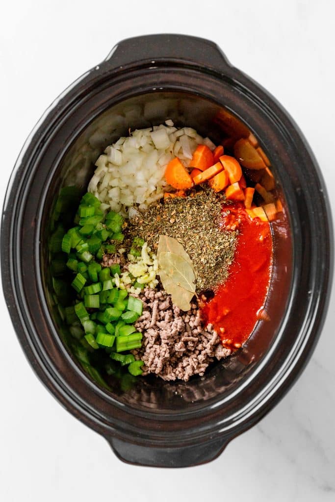 overhead shot of ingredients in a slow cooker to make spaghetti sauce.