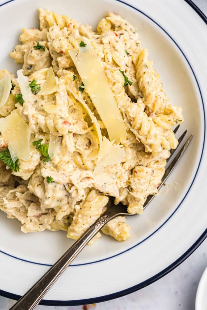 overhead shot of parmesan chicken pasta in a bowl with a fork.