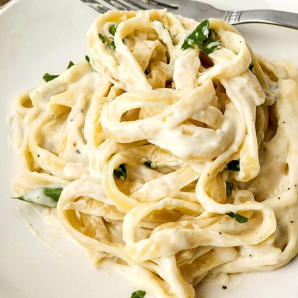 white plate of fettuccine alfredo.