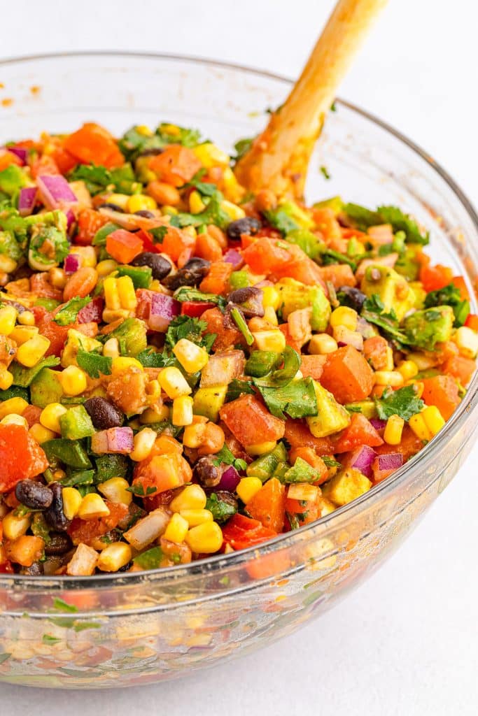 mixing bowl filled with cowboy caviar & a wooden spoon.