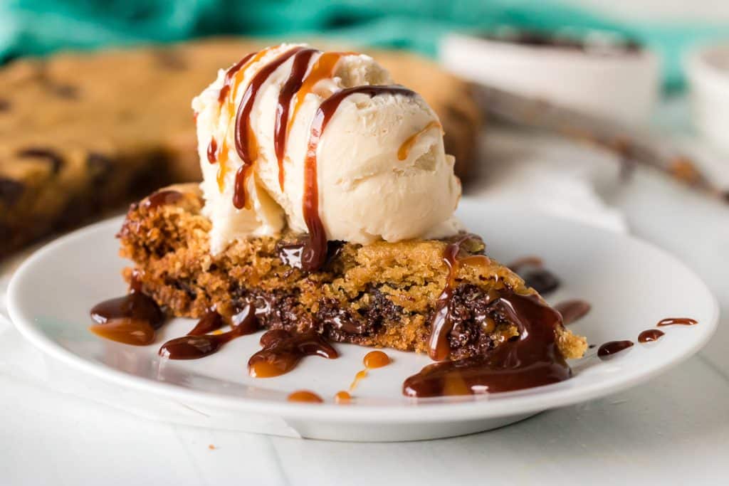 slice of chocolate chip cookie topped with ice cream and hot fudge.