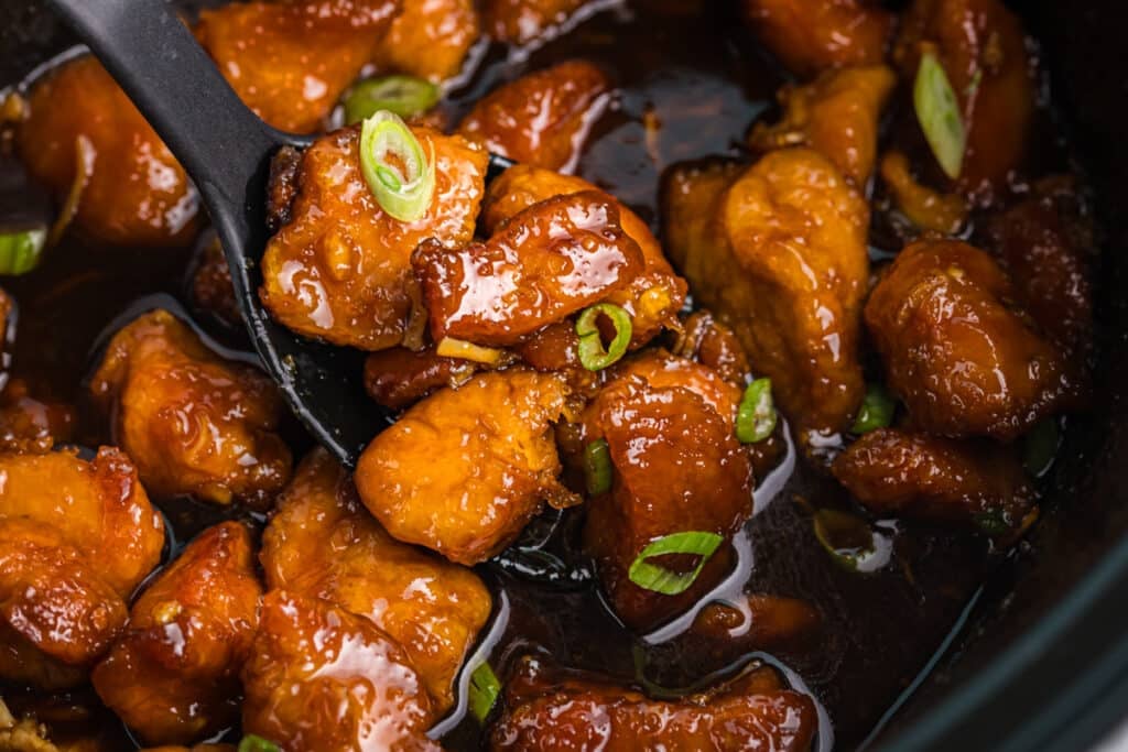 spoon lifting firecracker chicken from a slow cooker.