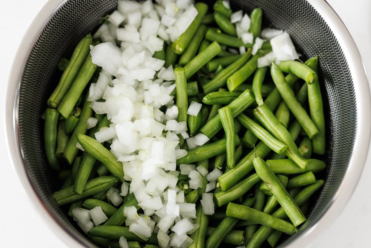 Diced onion and green beans in a pot.