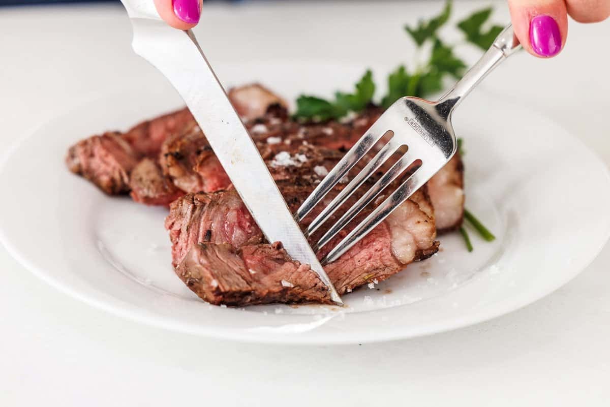 Cutting herbes de provence grilled porterhouse steak.