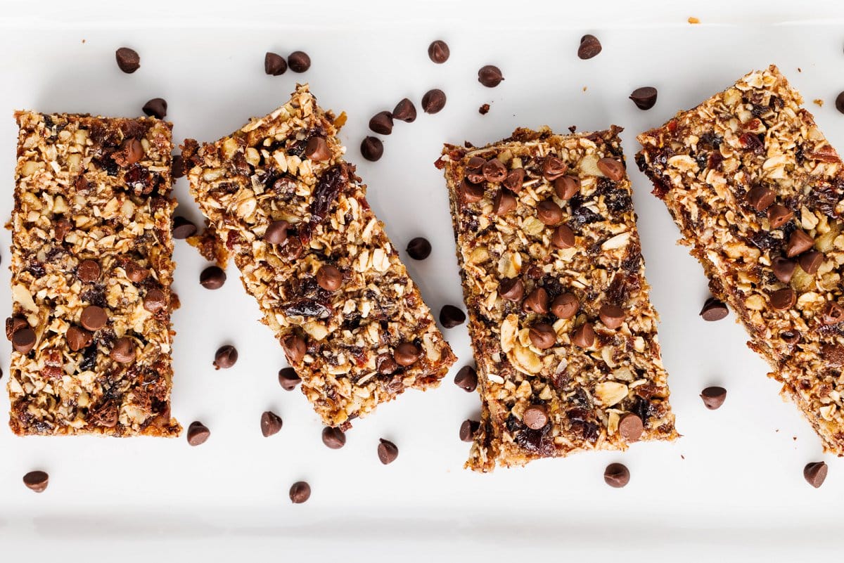 Four seedy oat and flax granola bars in a row on a white platter.