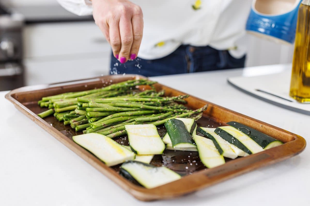 Seasoning asparagus and zucchini with salt.