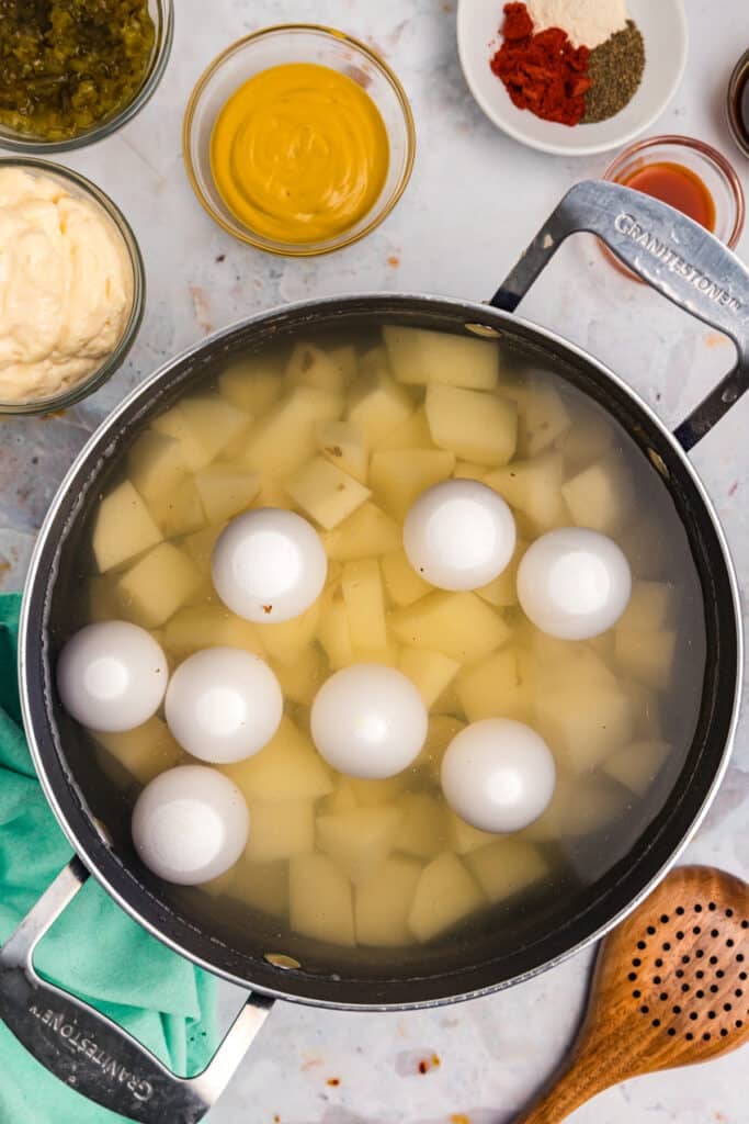 overhead shot diced potatoes and hard boiled eggs in a pot of water.