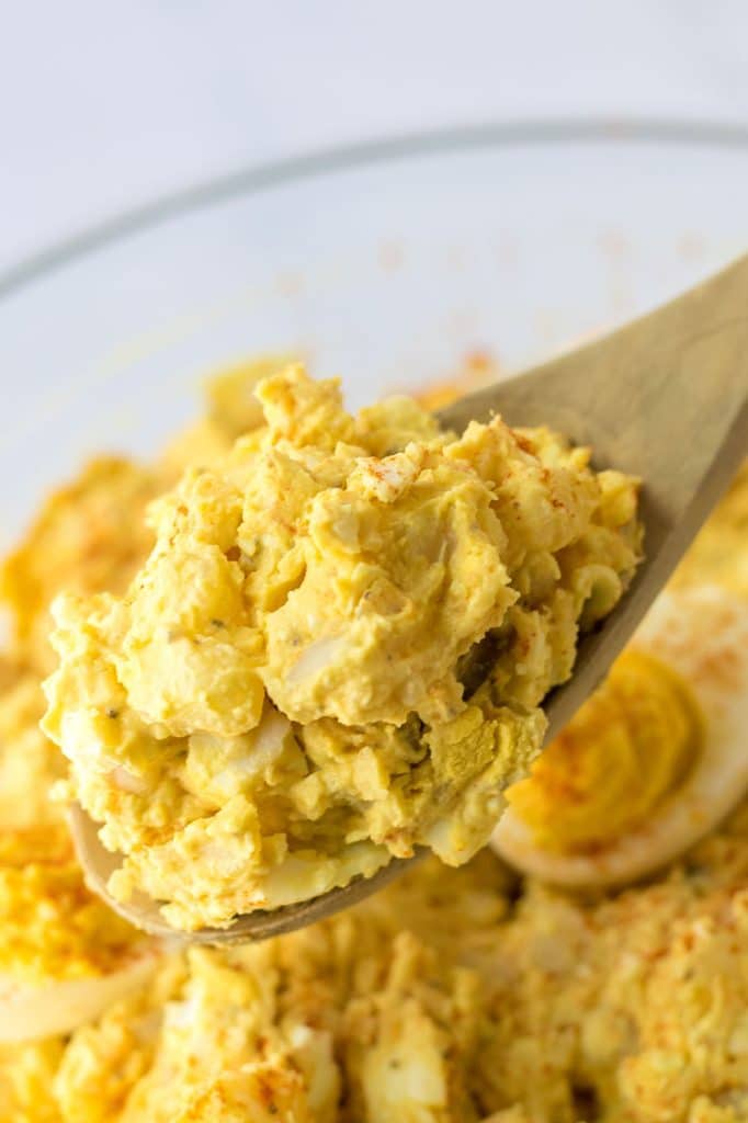 wooden spoon lifting a scoop of potato salad.