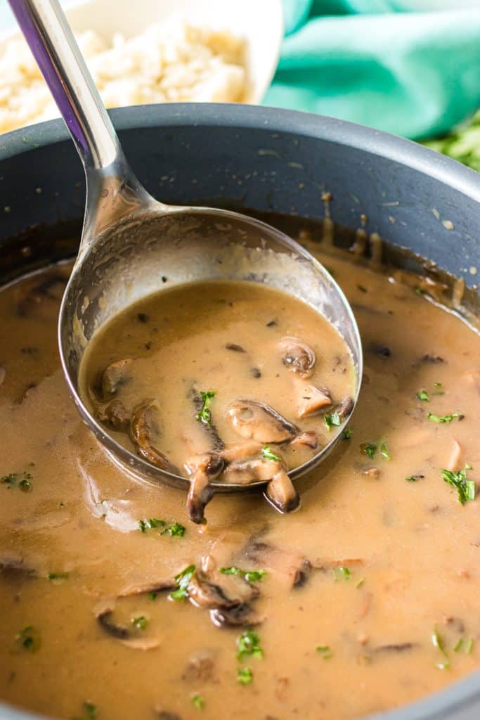 ladle scooping mushroom gravy from a pot.