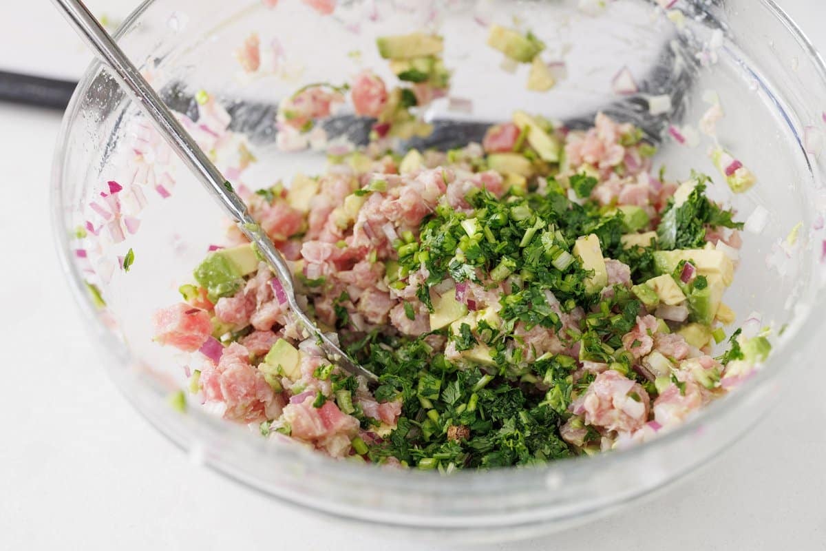 Minced cilantro added to bowl with tuna ceviche.