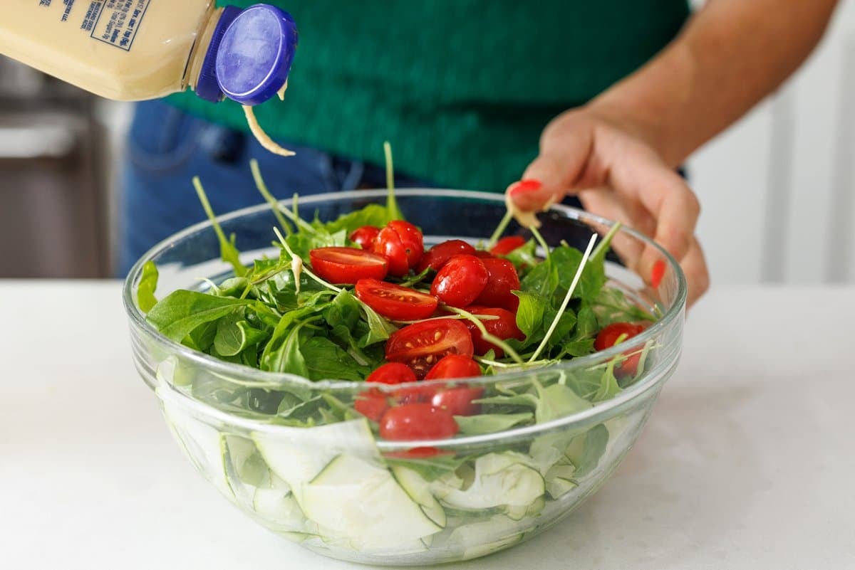 Adding Dijon mustard to a salad.