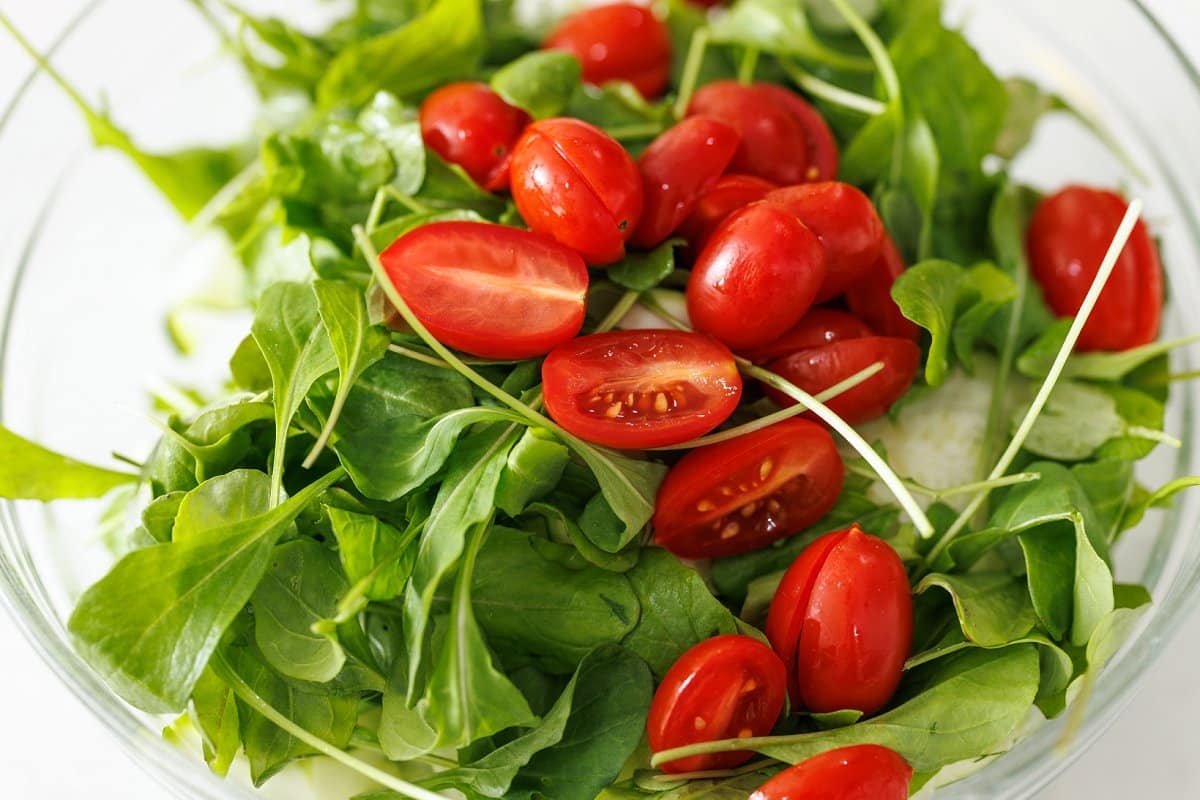 Halved grape tomatoes added on top of arugula.