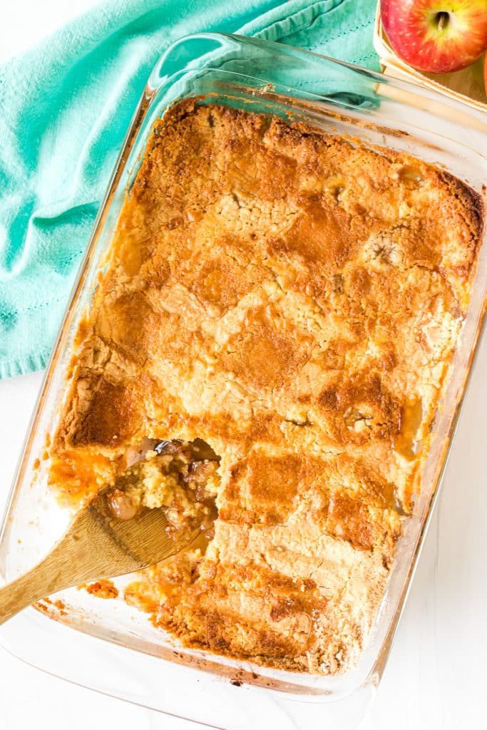 overhead shot of an apple dump cake with a wooden spoon scooping it.