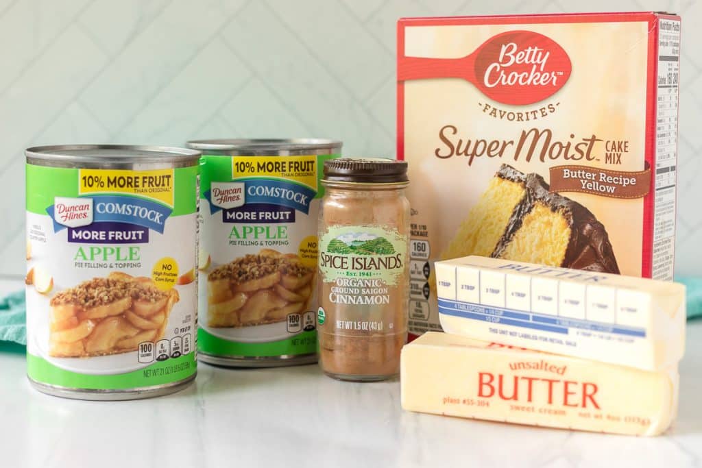 apple pie filling, cake mix, butter, and cinnamon laid out to make an apple cake.