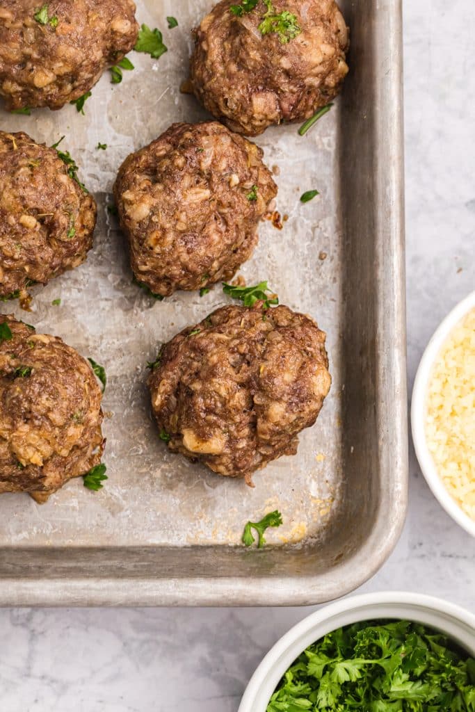 overhead shot of baked meatballs on a cookie sheet.