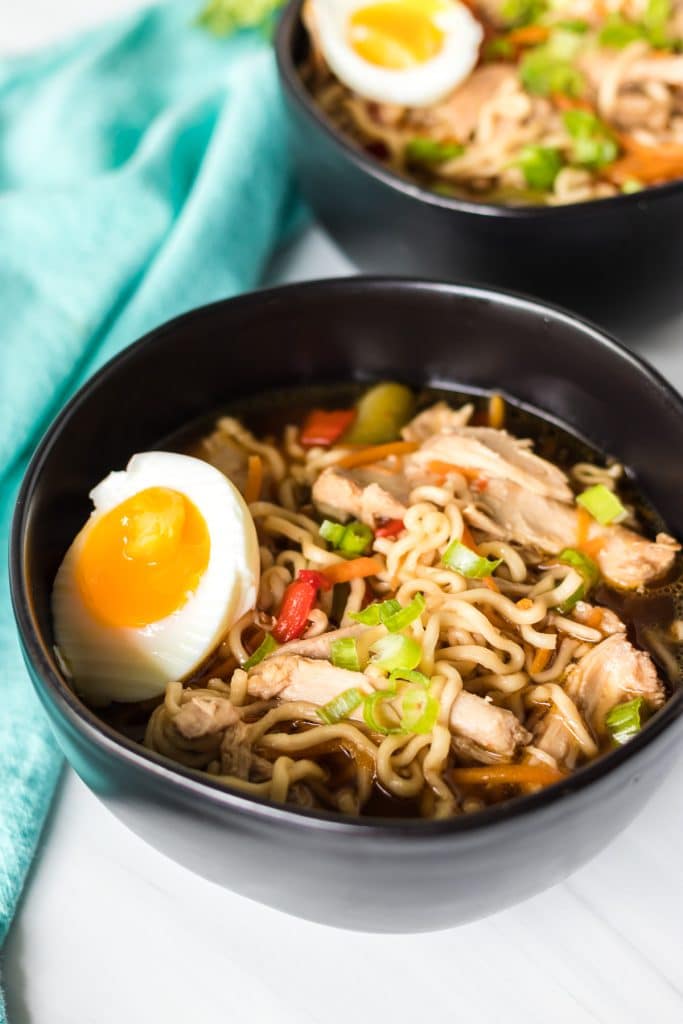 two black bowls filled with chicken ramen.