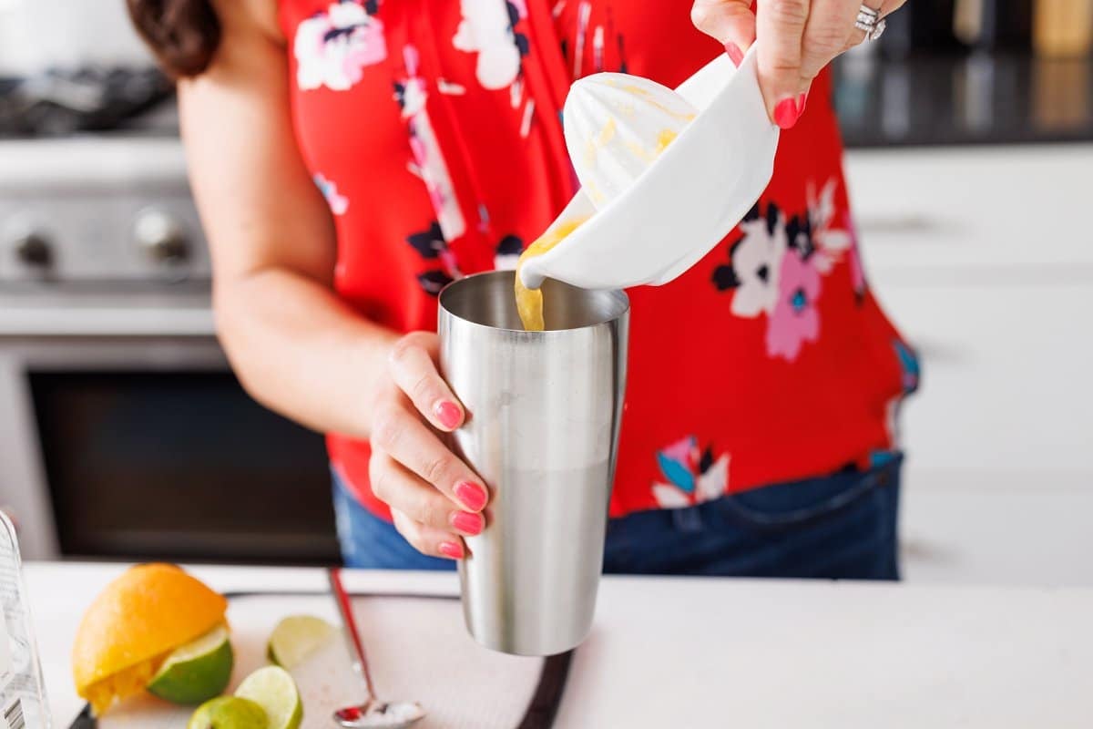 Pouring freshly squeezed orange juice into cocktail shaker.