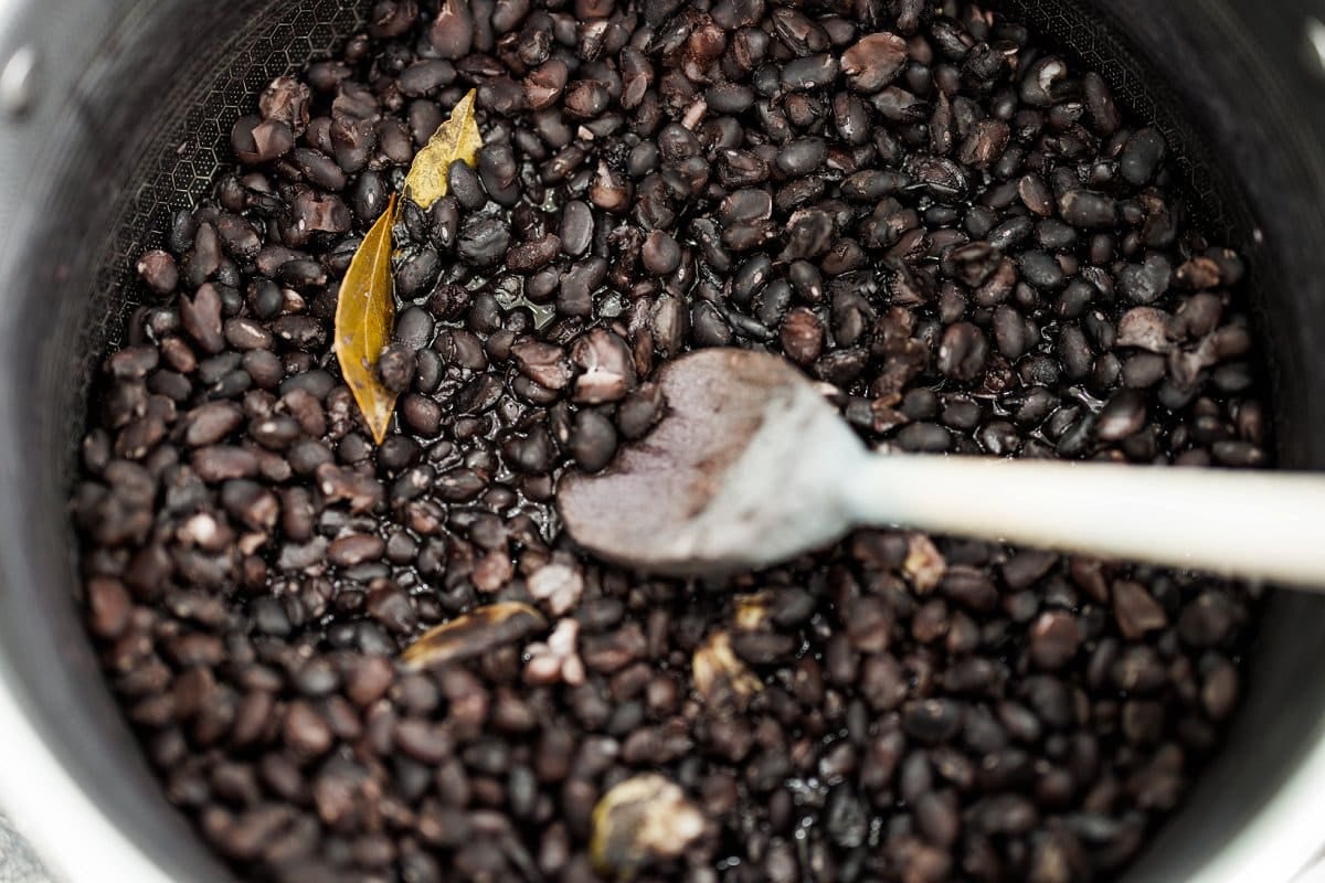 Stirring black beans with garlic and bay leaves.