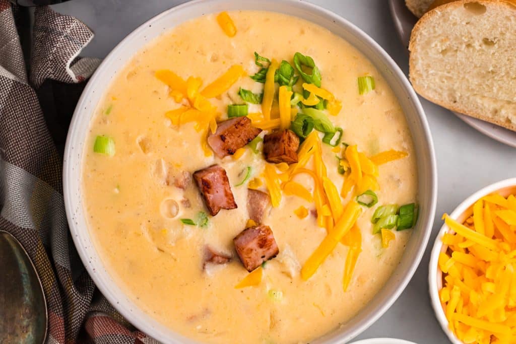 overhead shot of a bowl of cheesy potato soup topped with fried ham.
