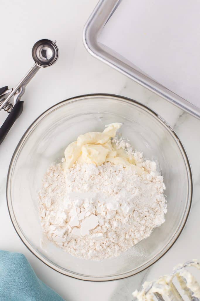 overhead shot of cookie dough and flour in a glass mixing bowl.